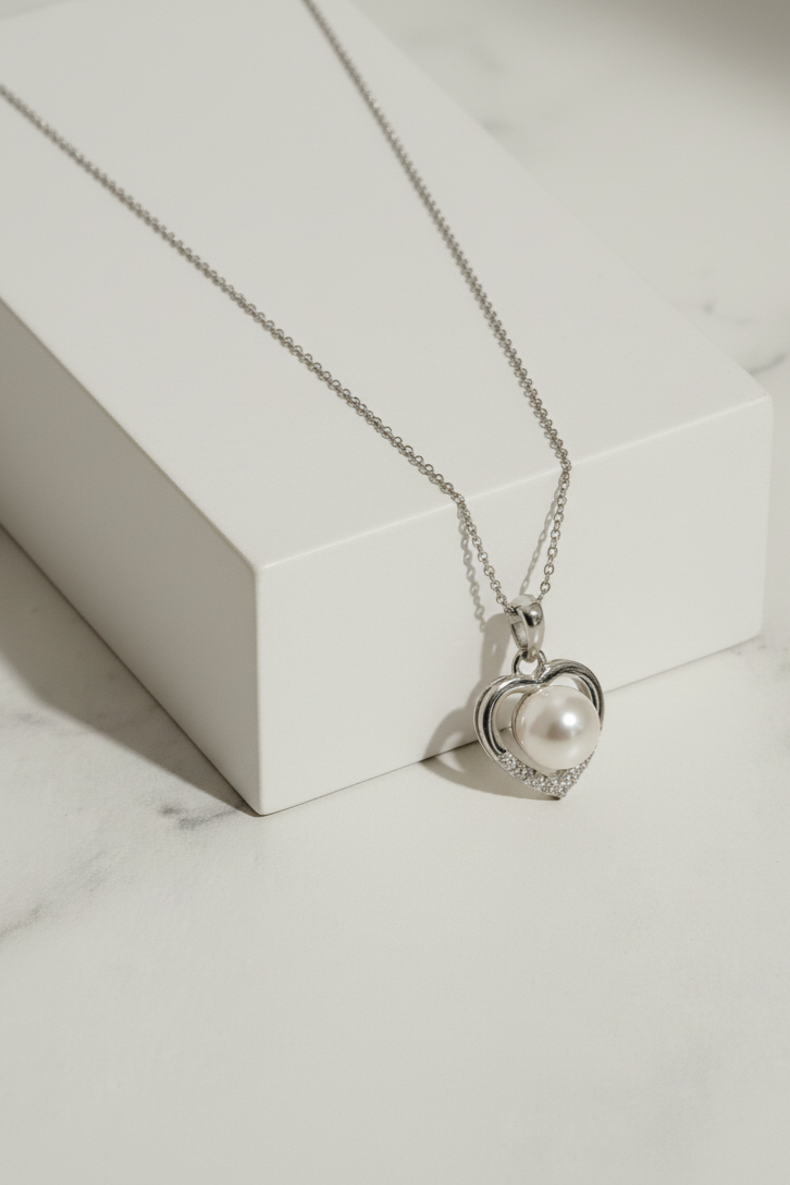 Heart-shaped necklace with a pearl pendant on a marble surface